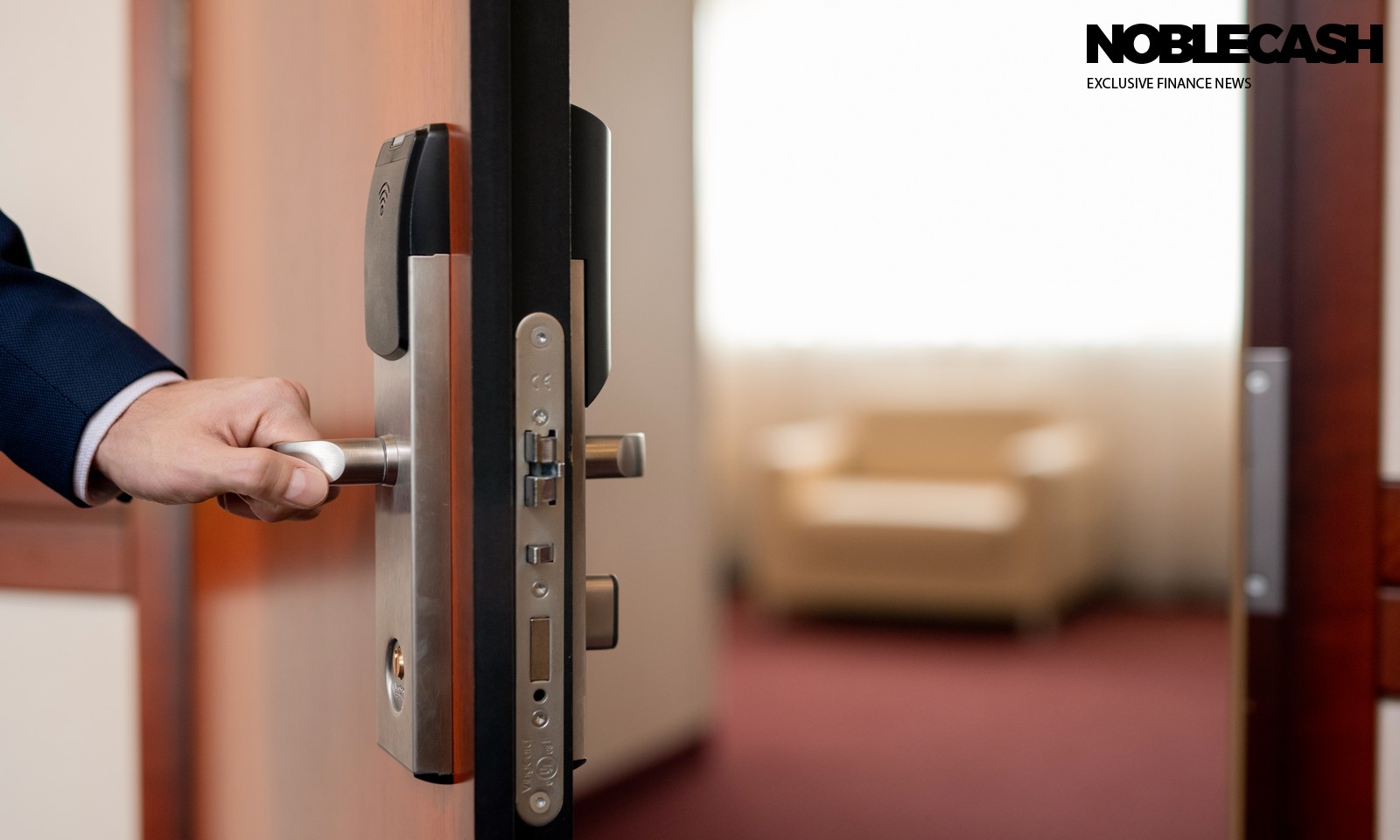 Human hand holding handle of wooden door while entering one of hotel room